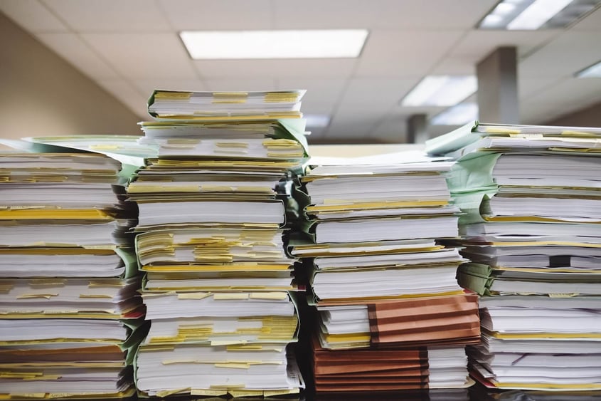 CAVU HCM. Stacks of payroll laws with sticky notes in between pages.